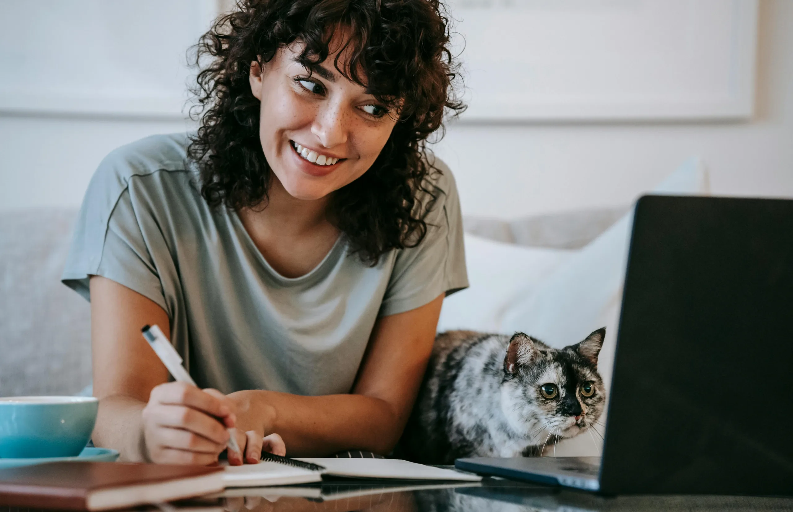 A woman thinking about ideas from the computer accompanied by her curious cat.