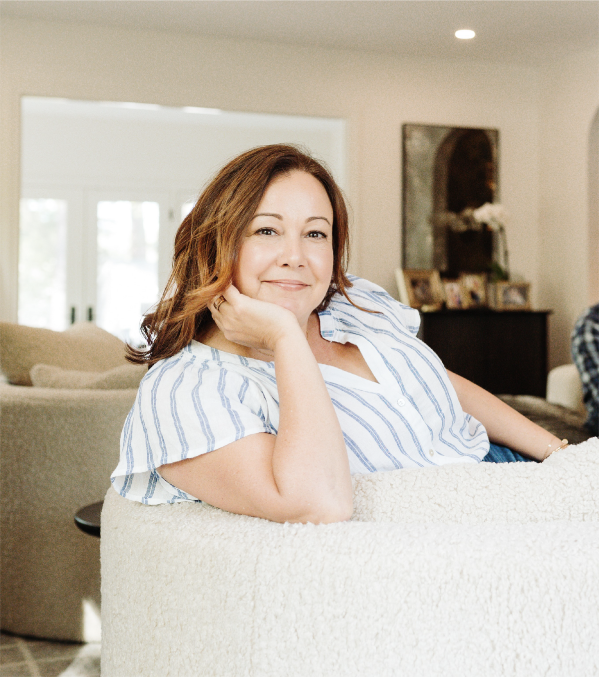 A profile picture Nicole Kalil, posing on a white couch with her hand resting under her chin.